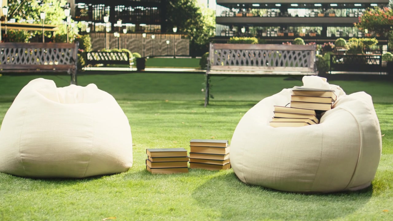 Diversi libri impilati e materiali di studio posizionati su un pouf all'aperto