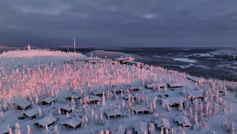 aerial view overlooking cabins on top of iso-syote fell, winter sunrise in finland