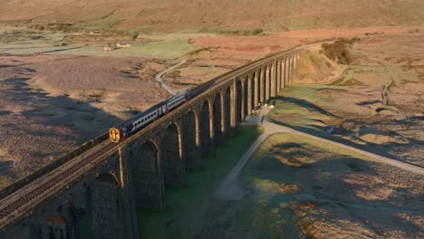 tren con dos vagones cruzando el puente del viaducto en una fría mañana de invierno