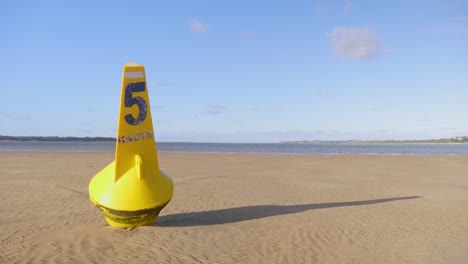 una boya de límite de velocidad que descansa en la arena durante la marea baja