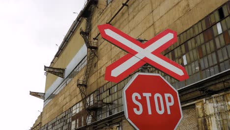 exterior view of abandoned soviet heavy metallurgy melting factory liepajas metalurgs territory, stop sign at railways, overcast day, medium panorama shot moving left