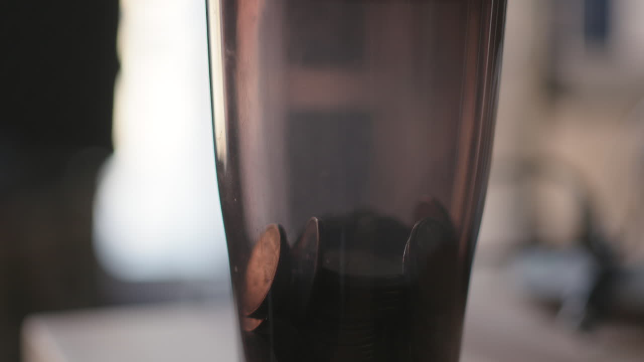 cierre de monedas cayendo en una taza transparente de cambio