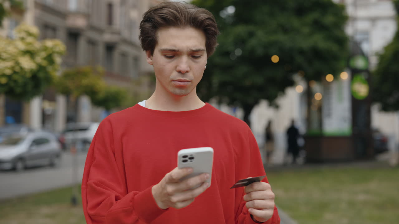 Man shopping online with mobile phone and credit card in urban environment