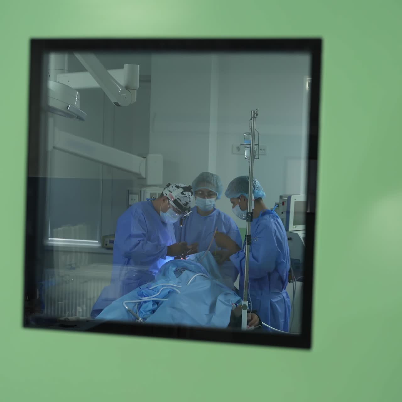 Medical staff healthcare system.Team of doctors with protective clothing performing an operation to a patient. COVID-19. View through the window