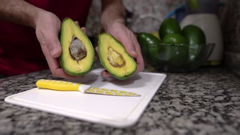 healthy cooking: male hands showing a fresh avocado in the kitchen