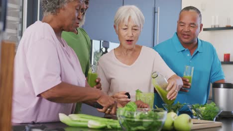 Happy-senior-diverse-people-making-healthy-drink-in-kitchen-at-retirement-home