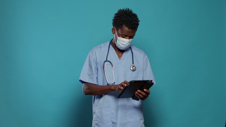 Assistente medico che utilizza tablet digitale indossando la maschera facciale