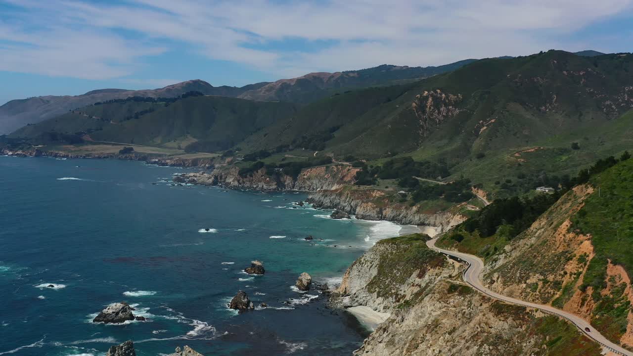 큰 산 절벽과 파도가 아래 바위에 부딪히는 캘리포니아 빅서 해안의 1번 도로를 따라 구불구불한 곡선 고속도로의 넓은 공중 전망