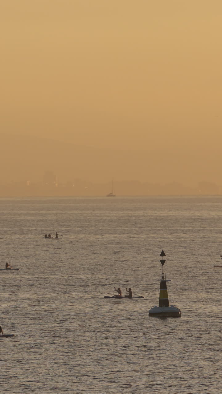 바르셀로나에서 새벽에 그림자 패들 서핑을 하는 사람들이 수직으로