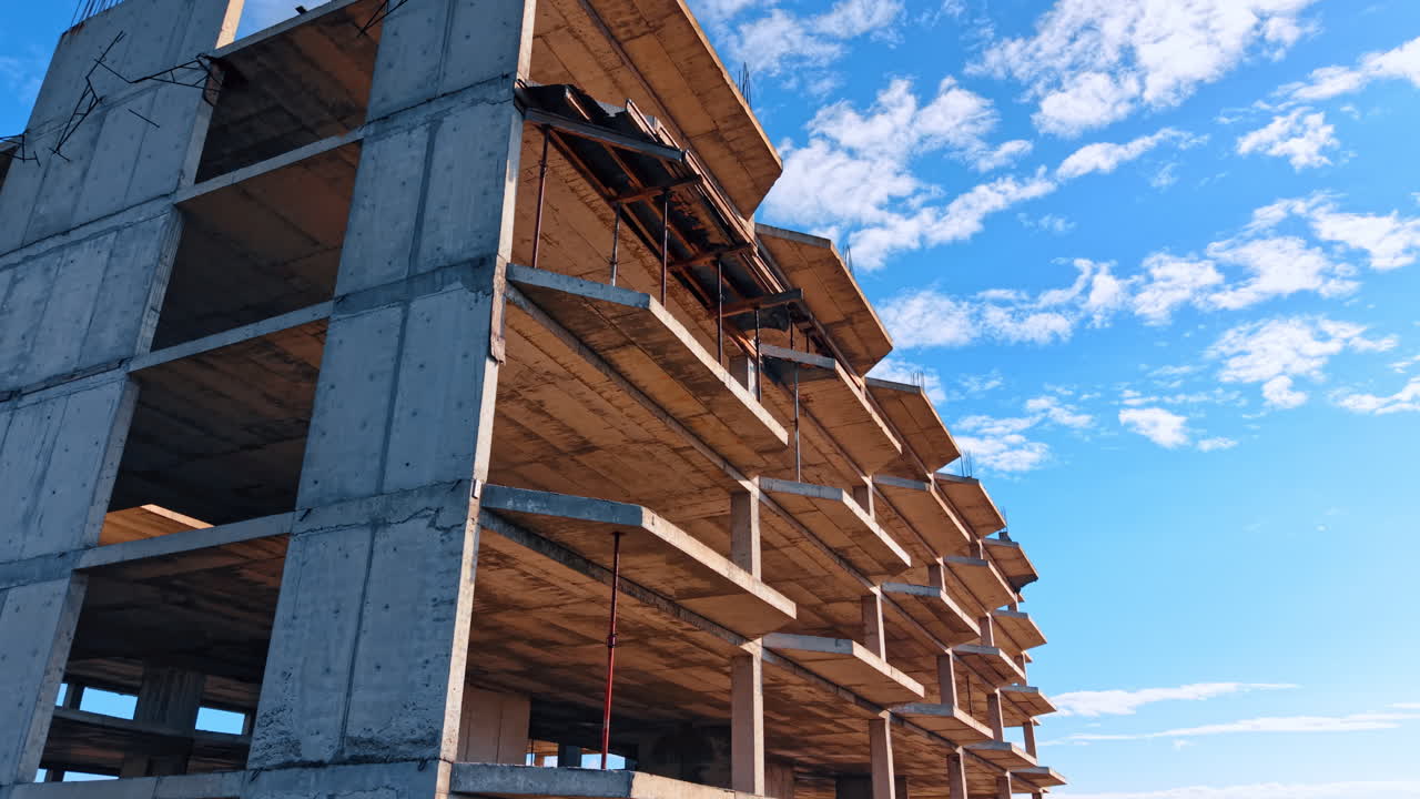 Unfinished multi-storied building façade exterior. Low angle view. Lovely blue sky with white clouds at backdrop