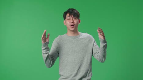 an asian man showing gesture hands palm saying wow and smiling in the green screen studio