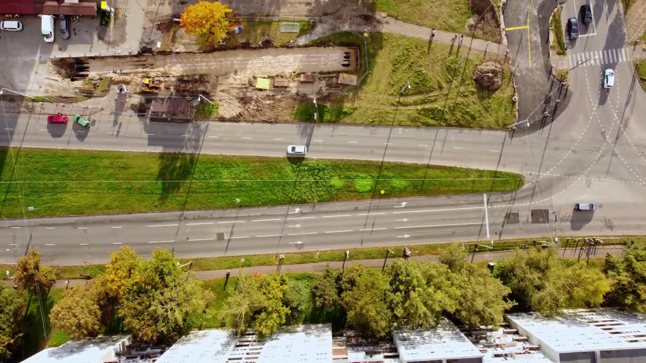 Road, green median, and construction site in purvciems neighborhood in autumn, aerial view
