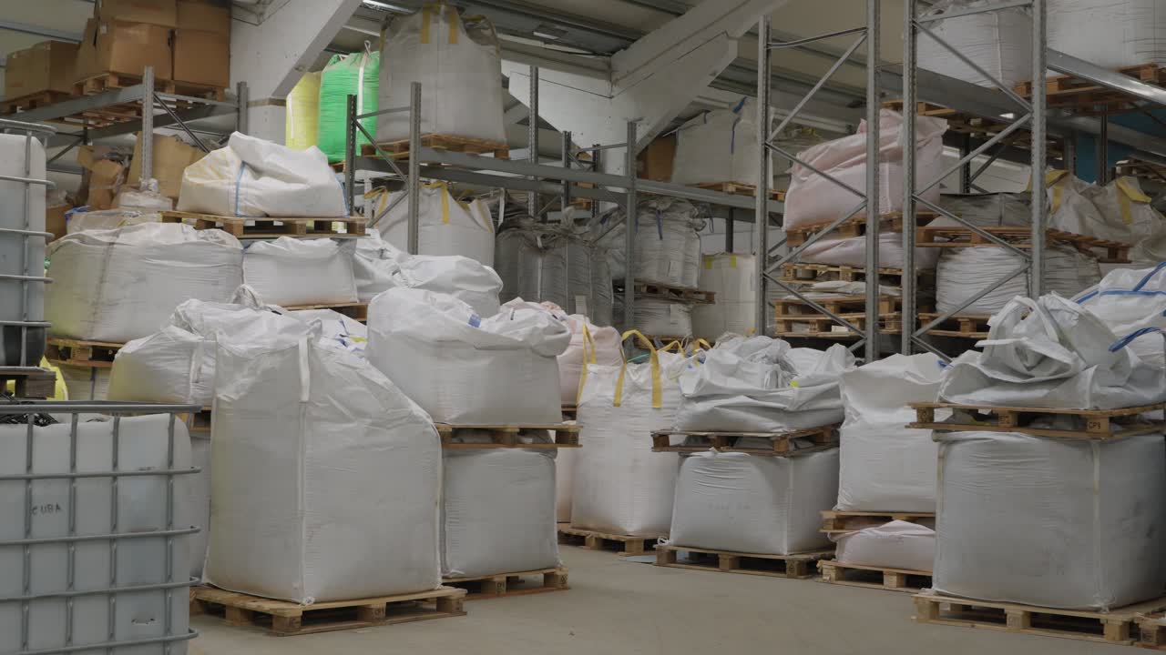 Large white bulk bags stored on pallets inside industrial warehouse facility
