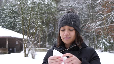 Junge-Asiatische-Frau-Putzt-Sich-Im-Kalten-Winterwald-In-Der-Schweiz-Die-Nase