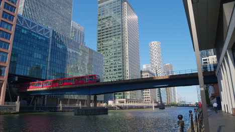 Docklands-Light-Railway-Train-Crossing-Bridge-Into-Canary-Wharf-Station-In-Finance-And-Business-District-Of-London-UK