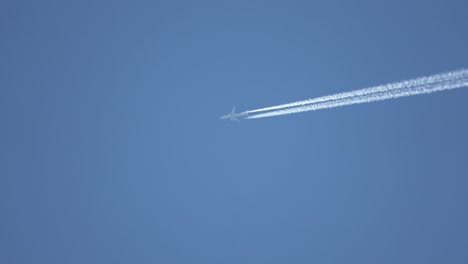 jet airliner flying high in the sky leaves contrails in the clear blue sky.