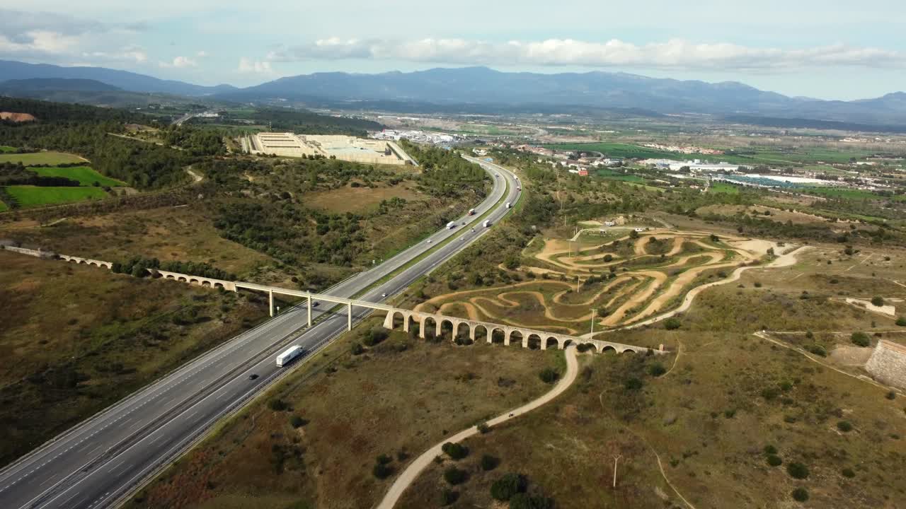 Aerial view of a highway with an aqueduct and motocross track in a rural landscape