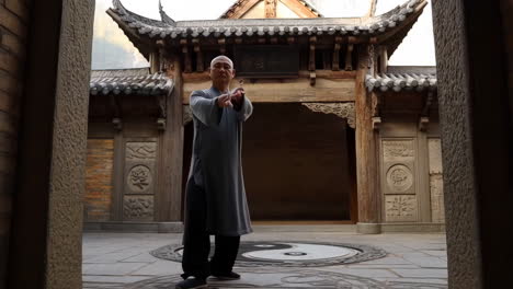man practicing tai chi in a traditional chinese temple courtyard