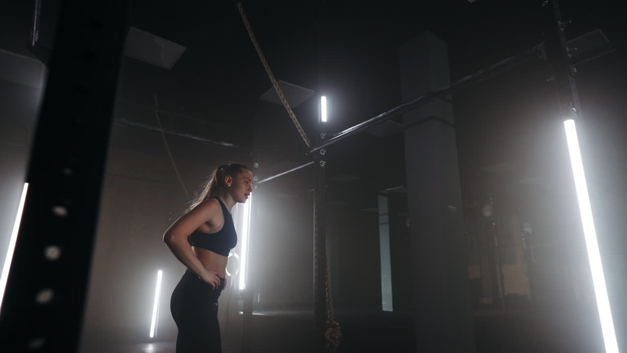 슬로우 모션: 피곤한 여성이 지구력 운동 후 훈련에서 힘을 회복합니다. 성공을 거두고 장애물을 통과하여 앞으로 나아갑니다. 강한 여성의 개념