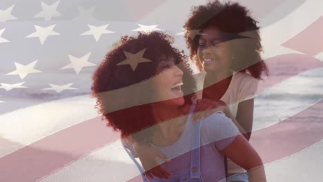 animation of flag of usa over happy african american mother with daughter on beach