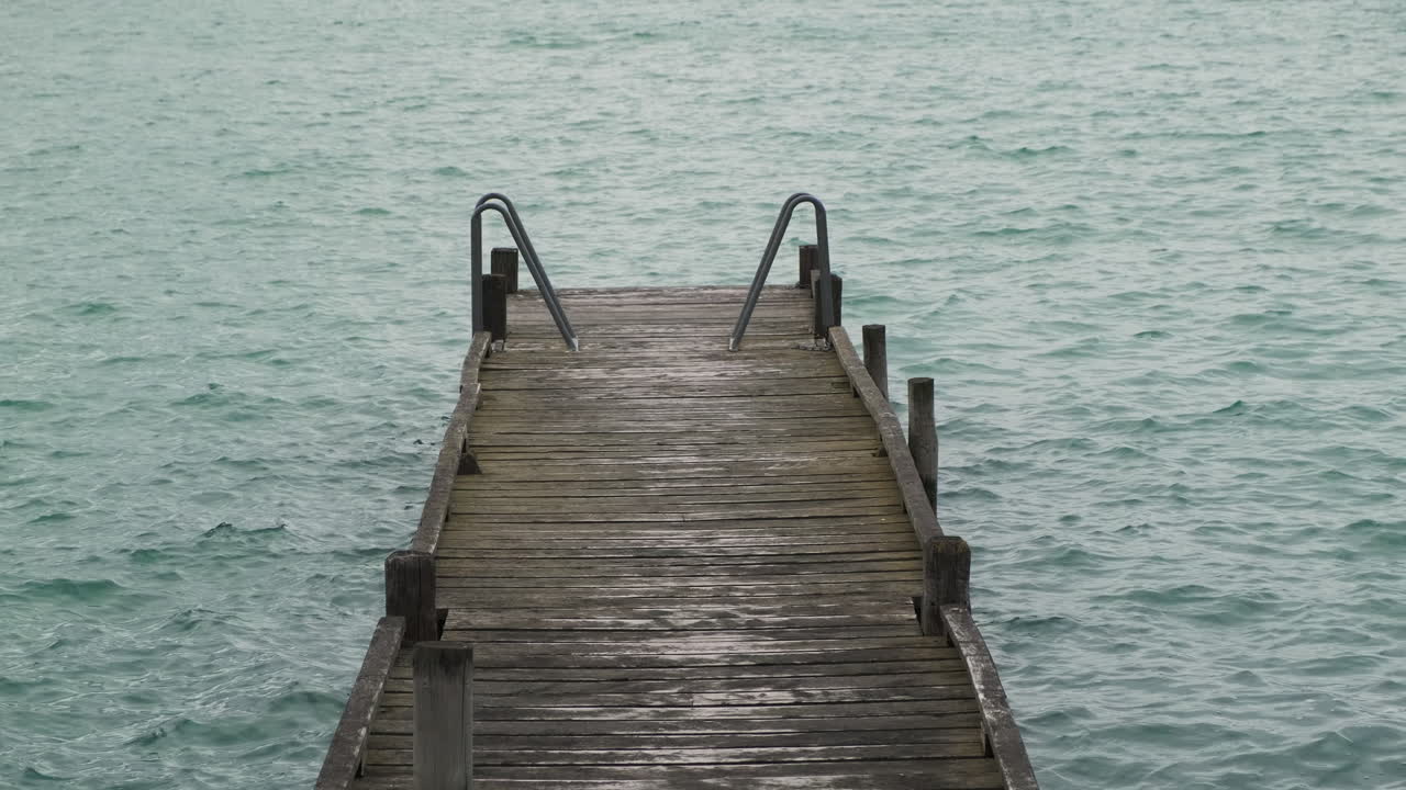 un muelle de madera se extiende hacia el tranquilo agua turquesa