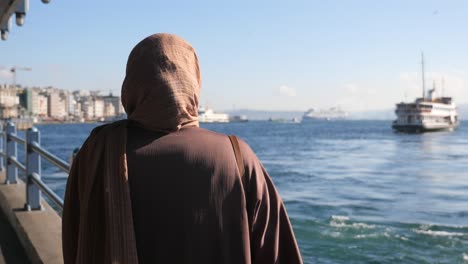 una mujer con hijab mirando el mar en estambul, turquía