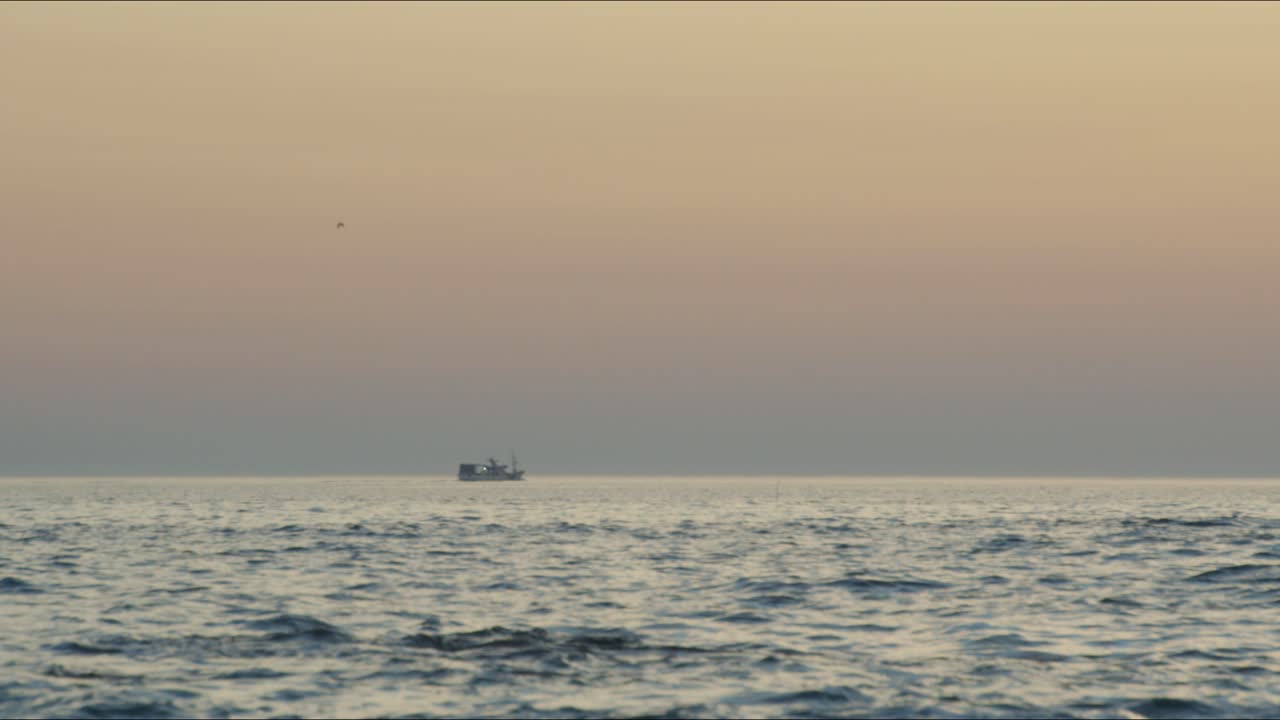 Ship crosses ocean during sunset on a beach in Portugal