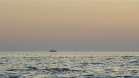 ship crosses ocean during sunset on a beach in portugal