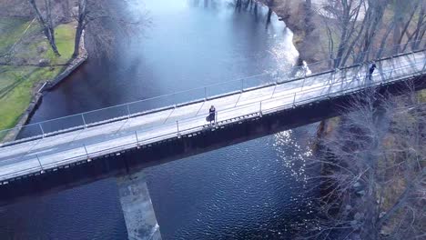 Aerial-young-women-standing-on-a-bridge-over-a-river