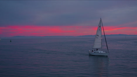 Segelboot-Auf-Dem-Ozean-Mit-Rosa-Und-Orangefarbenem-Sonnenuntergang-Mit-Blick-Auf-Die-Skyline-Mit-Inselbergen