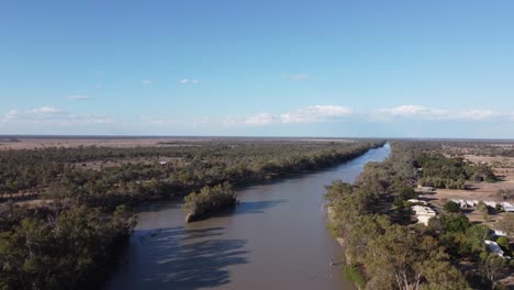 Drone-crossing-over-a-river-showing-a-small-island-and-a-town