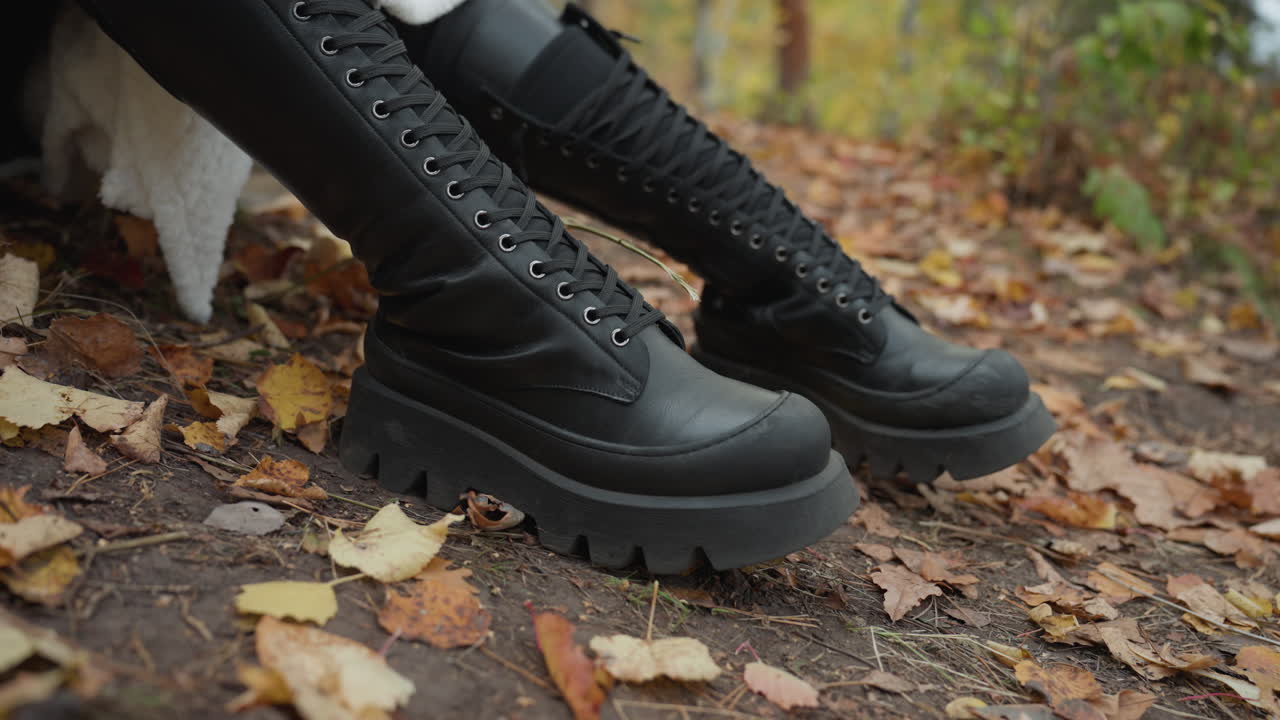 botas de couro grossas em close-up sobre folhas molhadas, modelo caucasiana transfere o peso em trilha na floresta, solas grossas pesadas pressionam o solo, cadarços detalhados e cano resistente, atmosfera editorial comercial, moda de rua