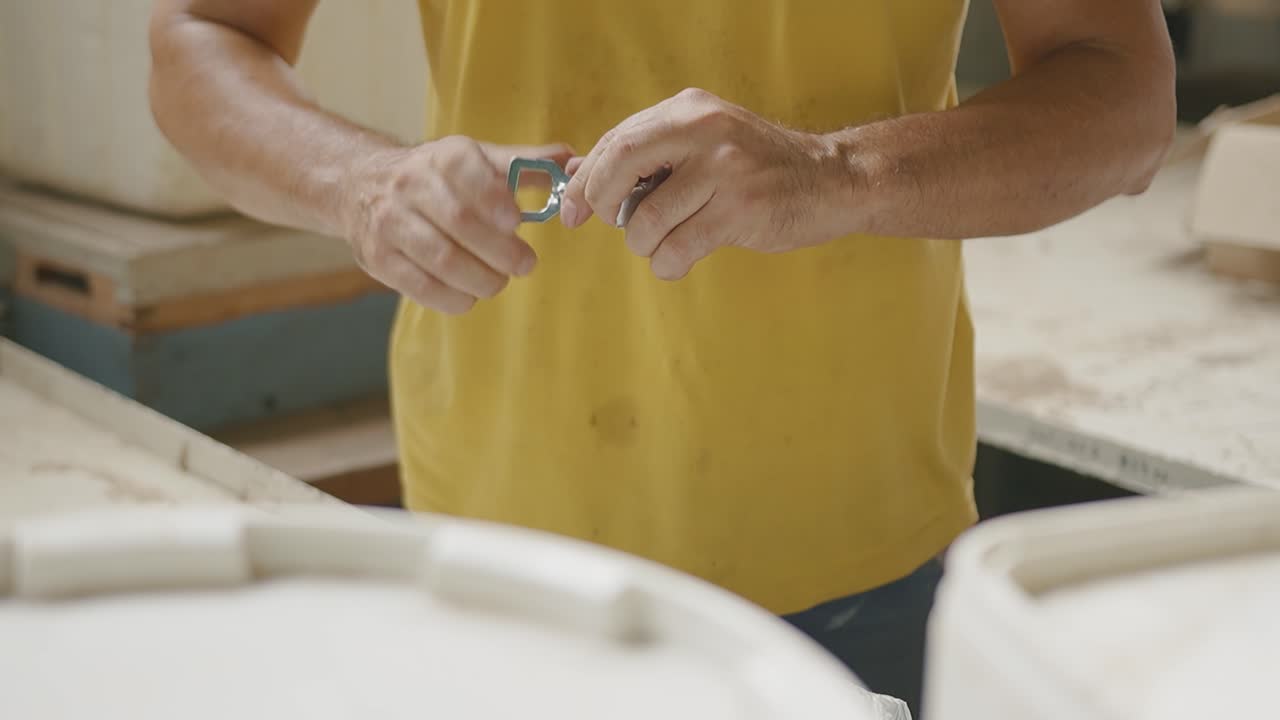Primo piano di mani che avvitano in un'officina, azione concentrata e costante