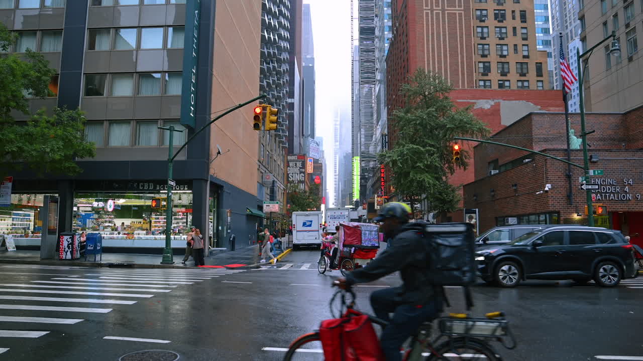 Walking by the street of New York on a rainy day. Cars, buses and rikshaws ride by the road