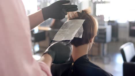 Manos-De-Un-Peluquero-Caucásico-Resaltando-El-Cabello-Del-Cliente-En-Papel-De-Aluminio-En-El-Salón,-En-Cámara-Lenta