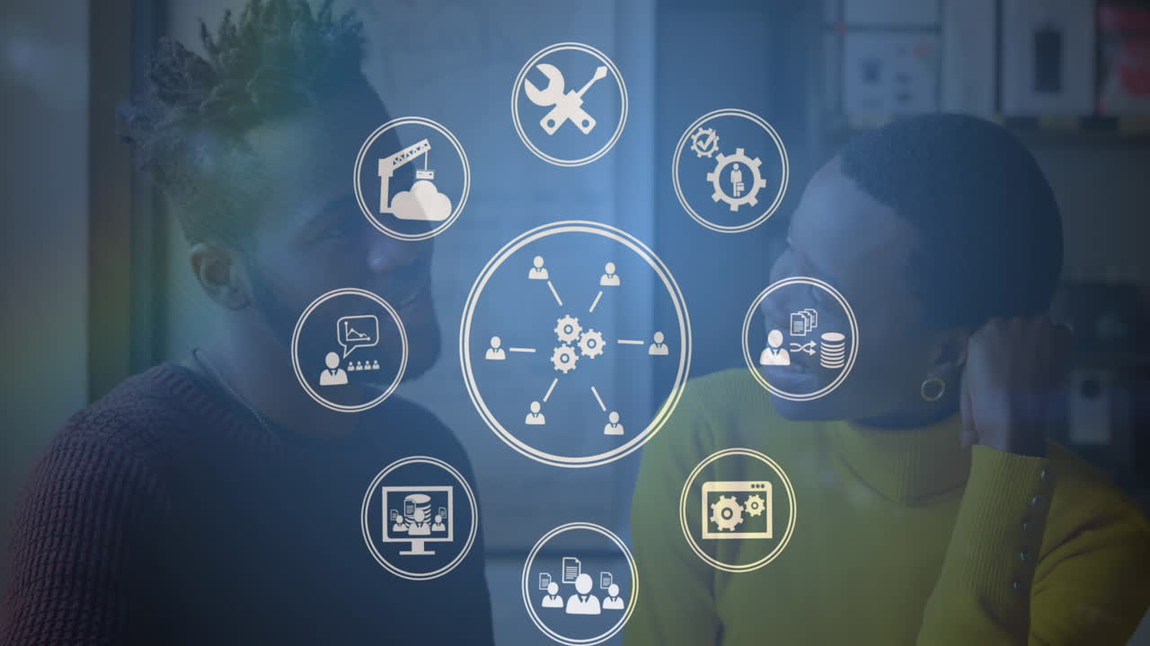 animación de iconos digitales girando sobre un hombre y una mujer afroamericanos hablando en la oficina