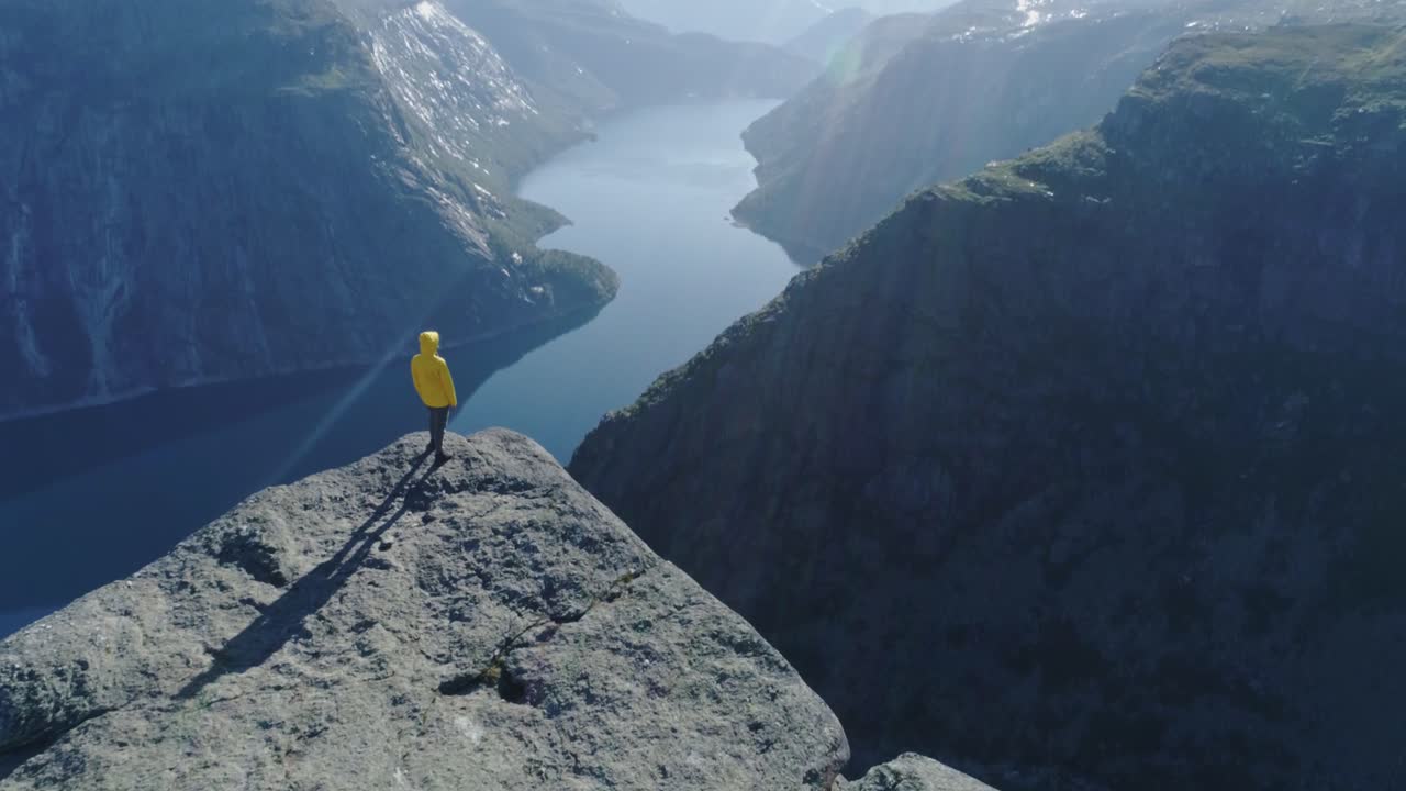 Cinematic view of woman on rocky edge overlooking fjord in Norway