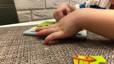 un niño pequeño organiza un rompecabezas en una mesa blanca