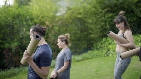 happy sporty people with yoga mats in park