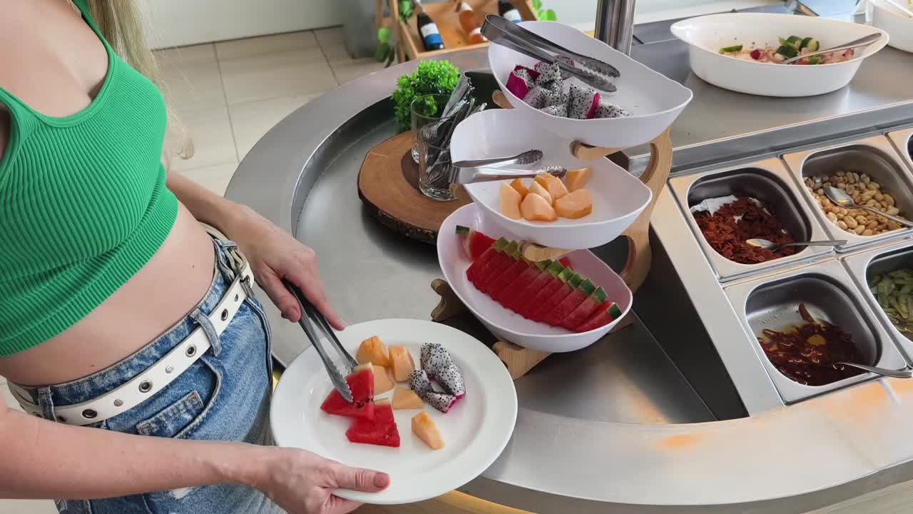 mujer comiendo ensalada de frutas en un buffet