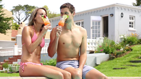 sexy couple sitting by the pool on holidays drinking cocktails