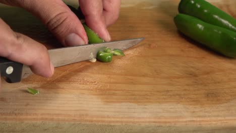 manos cortando un chile jalapeño en una tabla para cortar