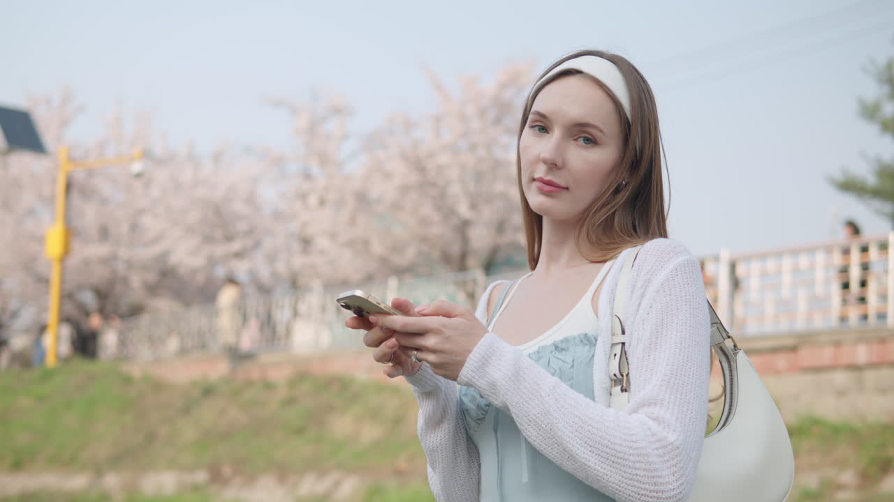 한국 서울시 서초구의 양재시민의 숲공원에서 휴대전화로 산책하는 젊은 여행자