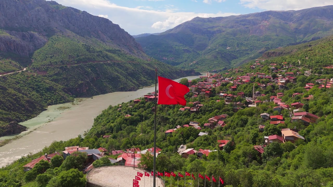Mavi gökyüzü altında Kemaliye köyü ve Fırat Nehri vadisinin yüksek açılı drone görüntüsü. Türkiye'de pitoresk kırsal dağ manzarası, yeşil tepeler ve tarihi bir seyahat destinasyonu.