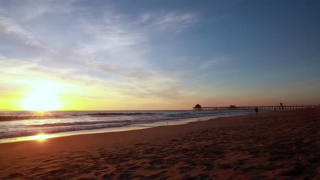 a gorgeous time-lapse of the beach during a yellow and blue sunset with the huntington beach pier in the background at surf city usa california