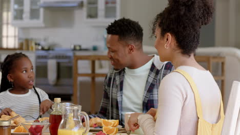 Happy-african-american-parents-and-daughter-having-breakfast-at-home,-slow-motion