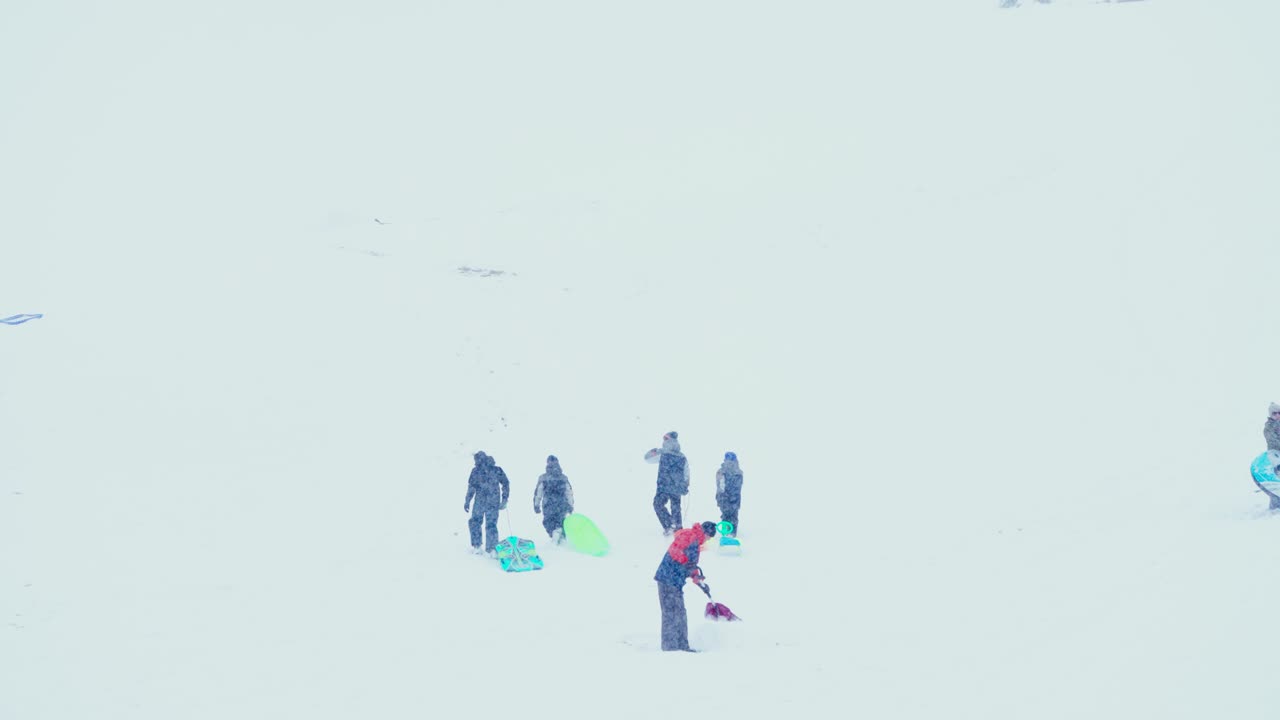 다시 내려올 준비가 된 썰매를 타고 오르막길을 걷는 가족