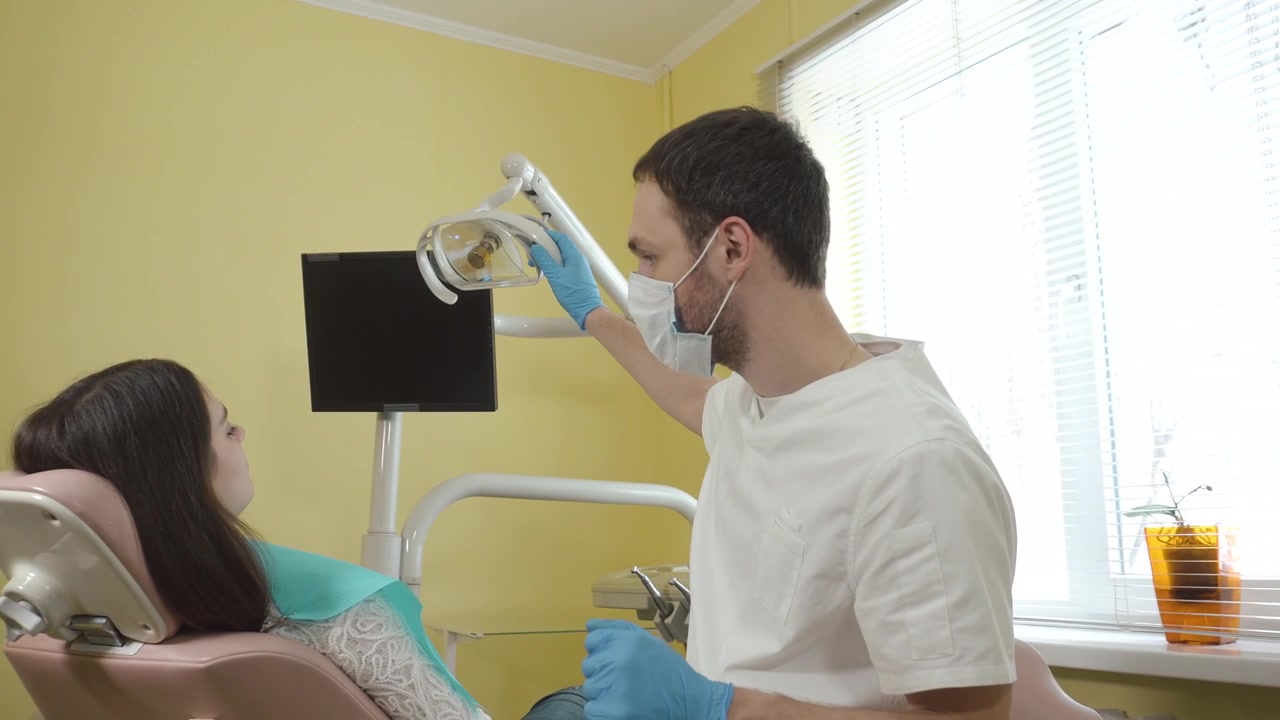 Dentista ajustando la luz a un paciente en clínica dental
