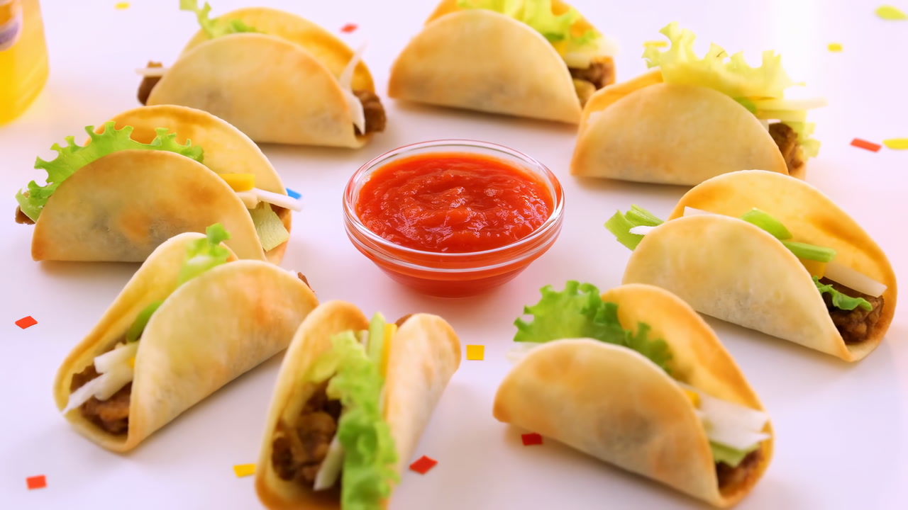 Mini Tacos Arranged Around Salsa Bowl On White Backdrop With Lettuce, Cheese, Seasoned Beef, Colorful