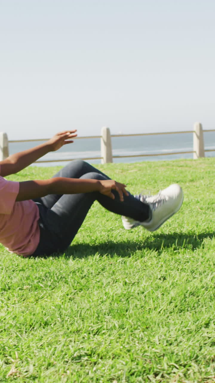 video de un feliz niño afroamericano haciendo rollos en el prado